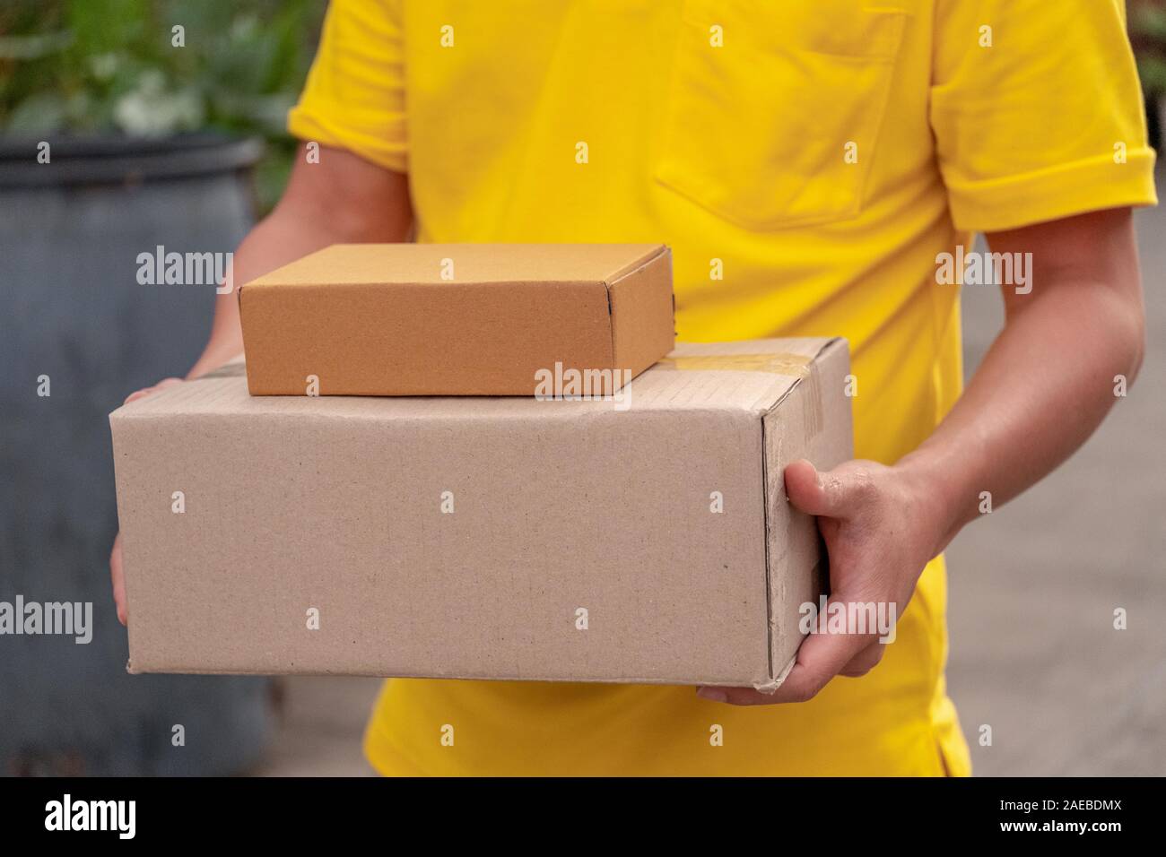 Giallo uomo consegna consegnare pacchi per i clienti.portalettere trasportare un carico di scatole. Foto Stock