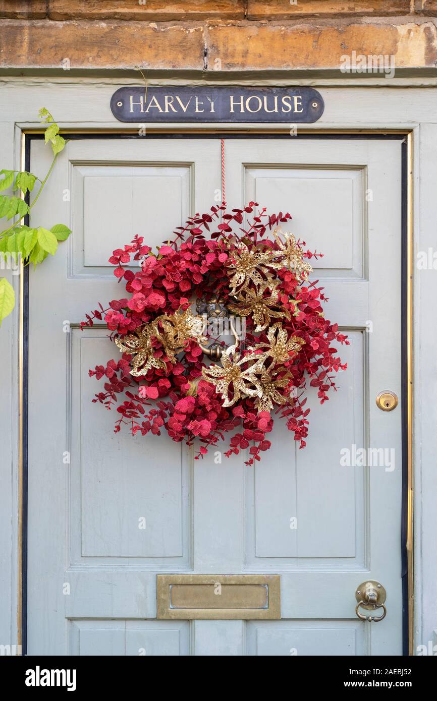 Rosso e Oro ghirlanda di Natale su un cottage porta in Moreton in Marsh. Cotswolds, Gloucestershire, Inghilterra Foto Stock