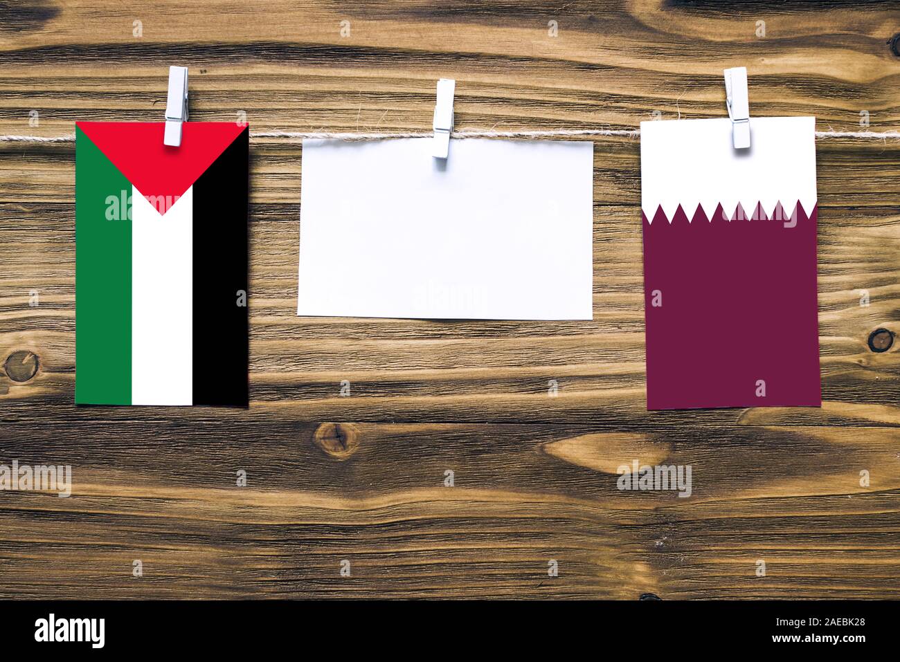 Appendere bandiere di Palestina e Qatar attaccata alla corda con vestiti perni con copia spazio bianco sulla nota carta su sfondo di legno.Le relazioni diplomatiche Foto Stock