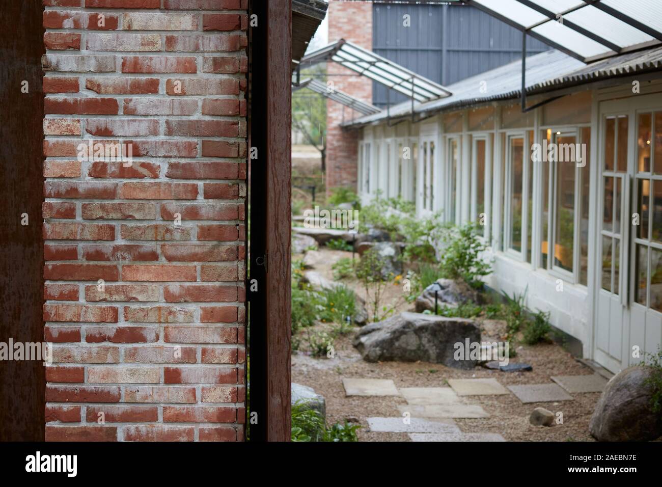 Una bellissima casa tradizionale con un muro di mattoni in un giorno di pioggia Foto Stock