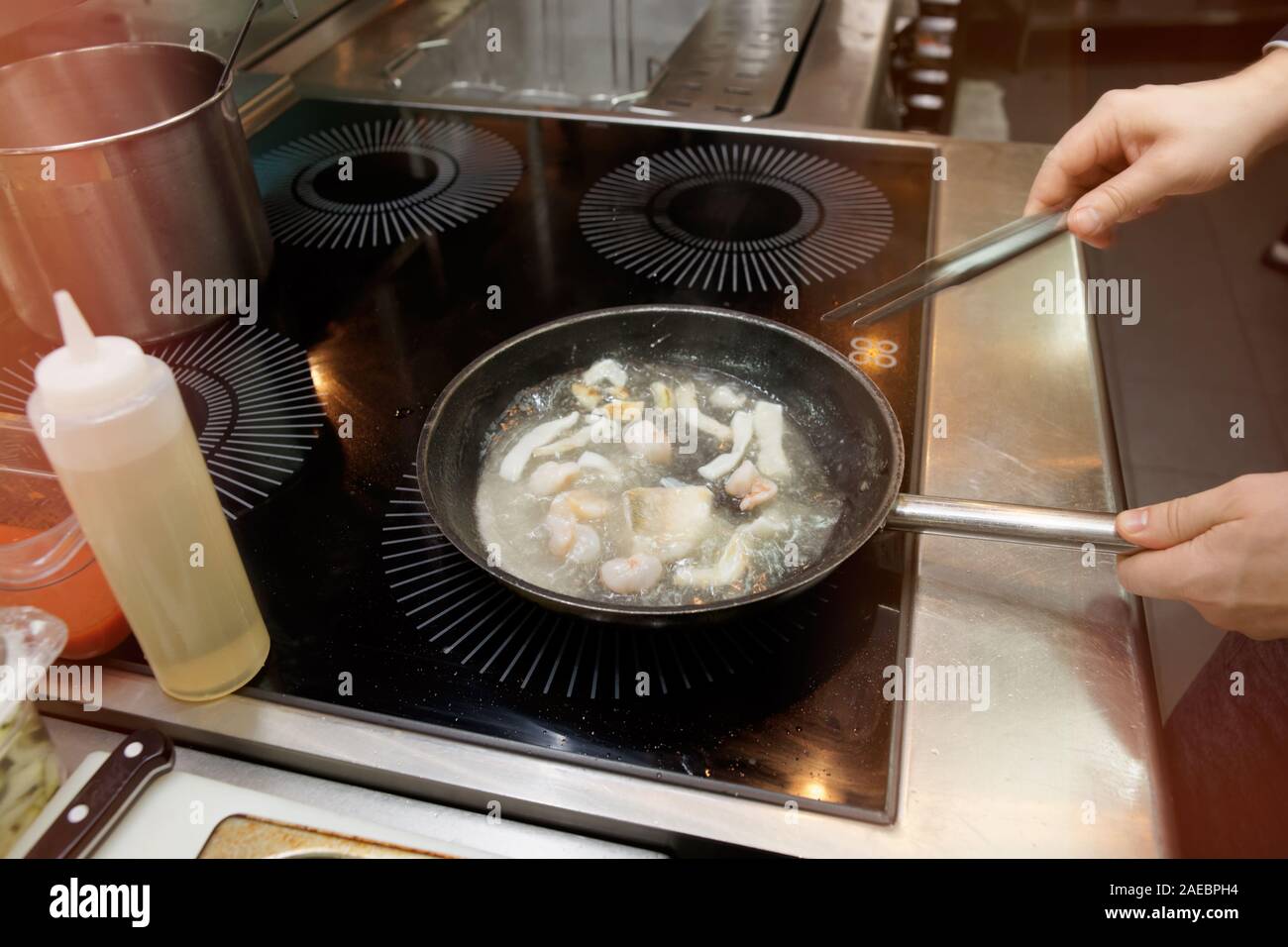 Lo chef è cucina di pesce e frutti di mare in brodo bollente a cucina professionale, tonica immagine Foto Stock