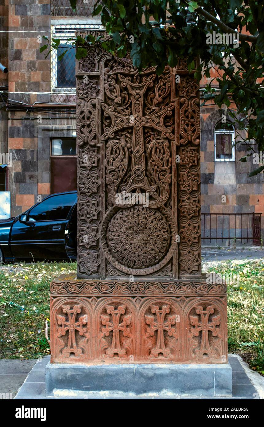 Grigio con sfumature rossastre khachkar pietra con una grande croce traforata in un telaio di vimini con un cerchio-un simbolo di eternità sul vicolo di croci in Gy Foto Stock