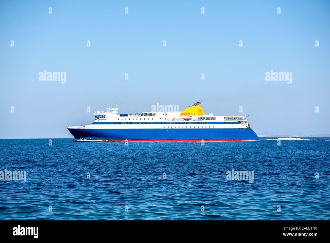 Big Blue traghetto galleggiante sul mare Egeo sotto un cielo blu chiaro. La Grecia Foto Stock