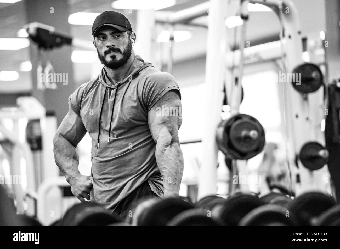 Sport training motivazione concetto forte giovane atleta maschio con la barba in posa davanti a uno specchio in una palestra per il fitness club con attrezzature sportive Foto Stock