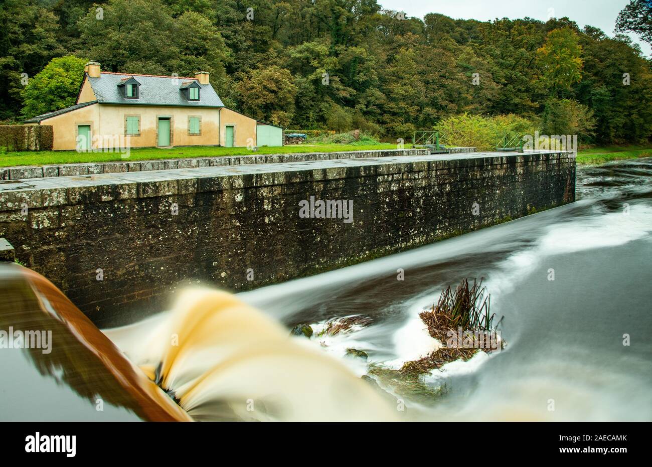 Una lunga esposizione sulla serratura di un canale. L'acqua fangosa sgorga dalla diga del secondo blocco di rivestire Natous sul canale da Nantes a Brest Foto Stock