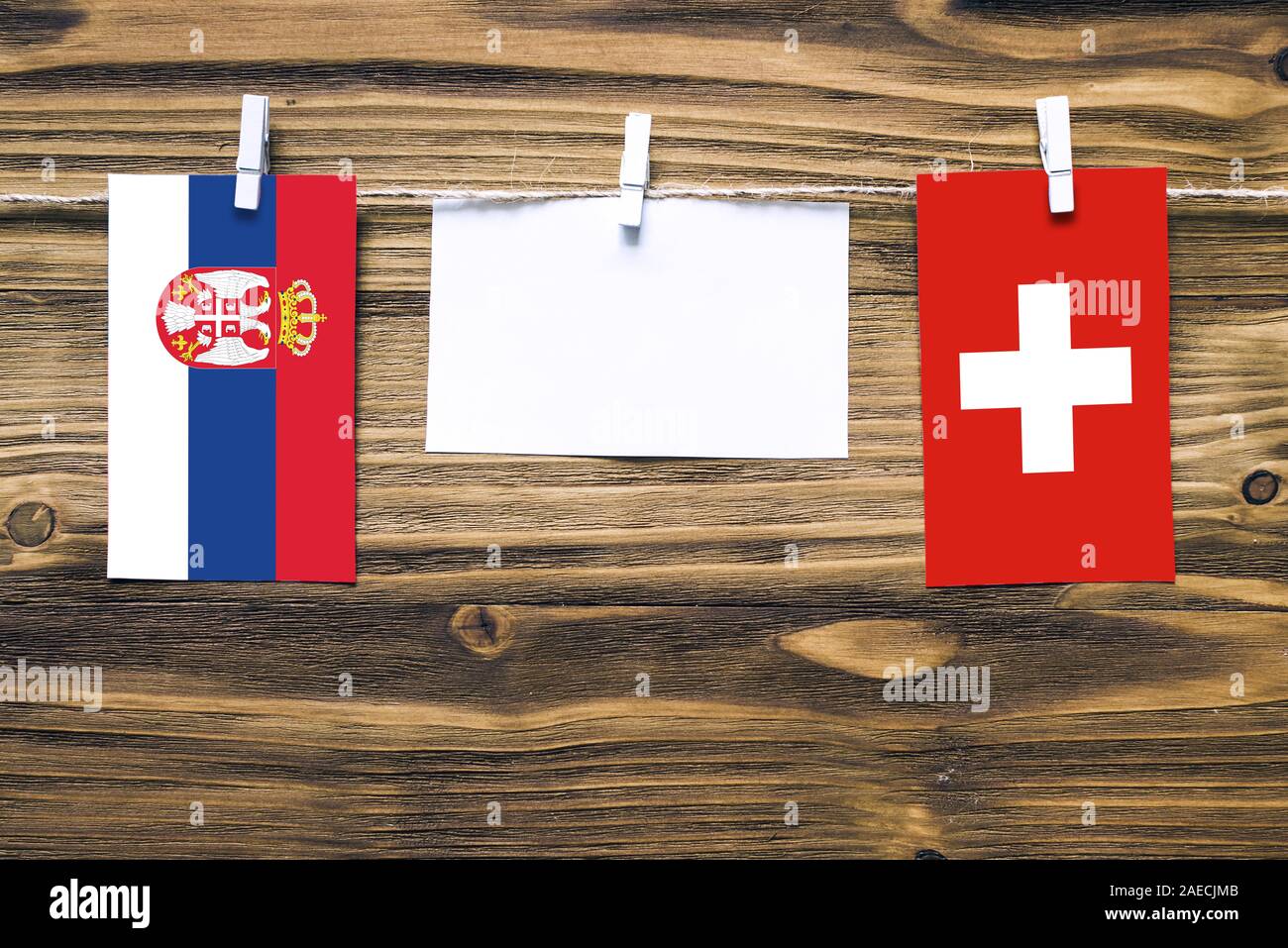 Appendere bandiere di Svizzera e Serbia attaccata alla corda con vestiti perni con copia spazio bianco sulla nota carta su sfondo di legno.Diplomatic relatio Foto Stock