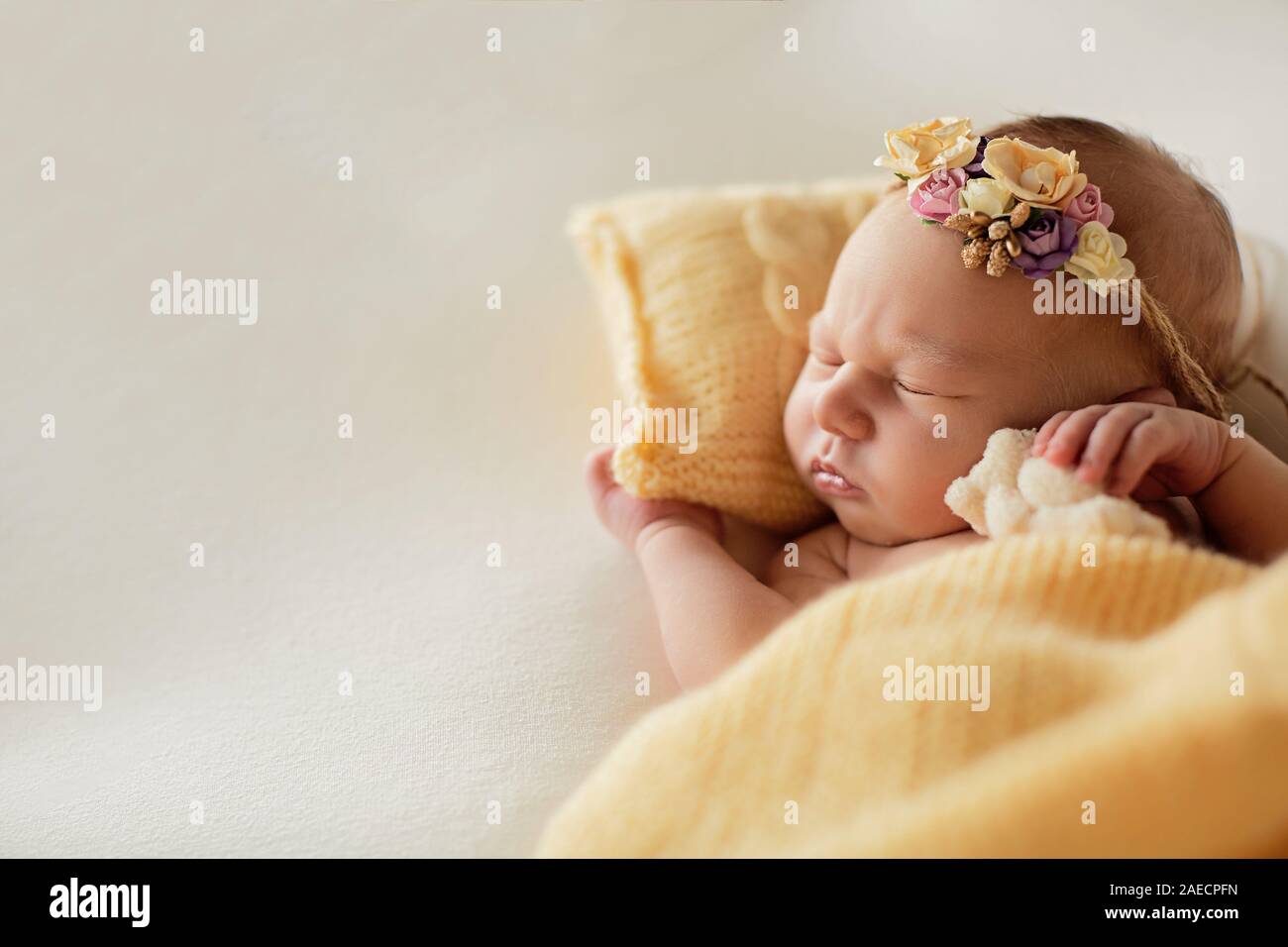 Neonato sul cuscino di colore giallo con un cerchio sulla testa Foto Stock