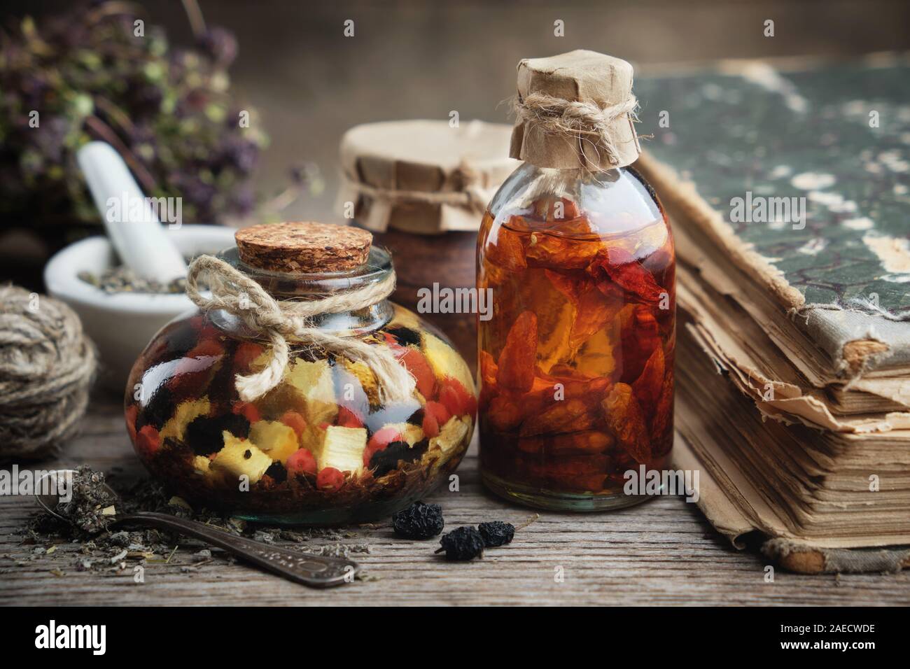 Bottiglie di olio essenziale o infusione, malta e vecchio libro. La medicina di erbe. Foto Stock