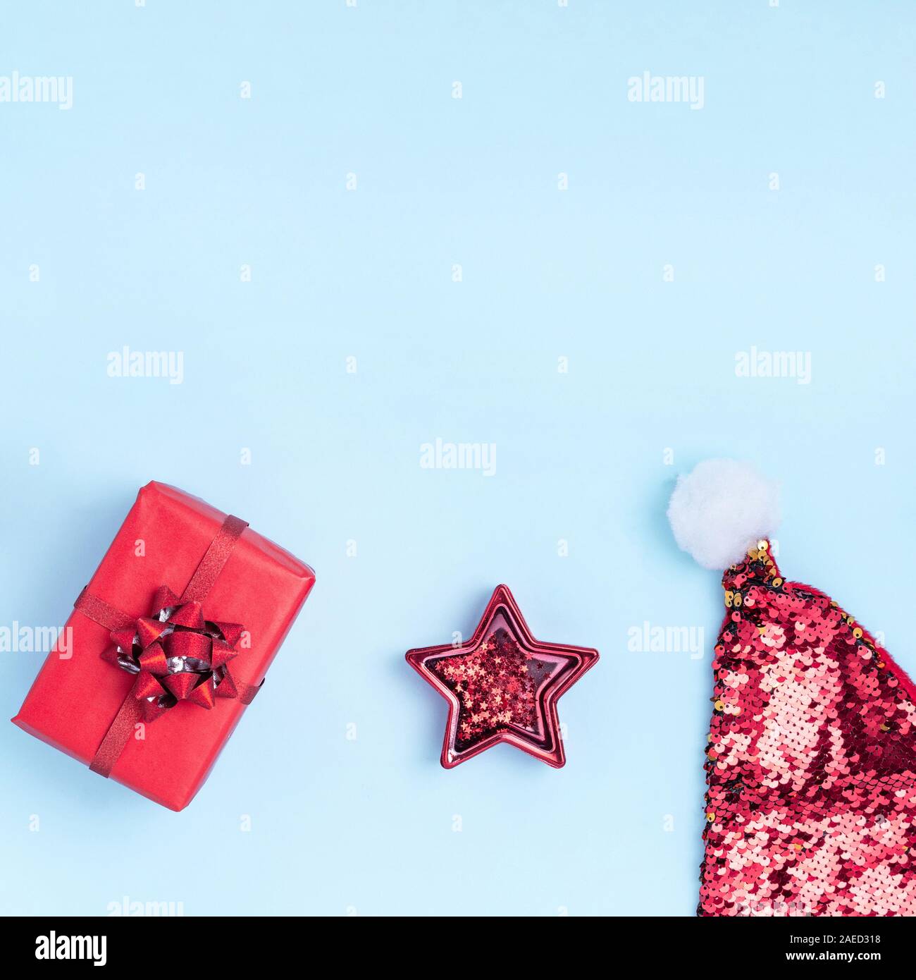 Nuovo anno e composizione di Natale. Il telaio da palle rosse, stella rossa, confezioni regalo, Santa's hat e brilla sul pastello blu sfondo della carta. Vista superiore, piatto laico, copiare lo spazio, formato instagram Foto Stock