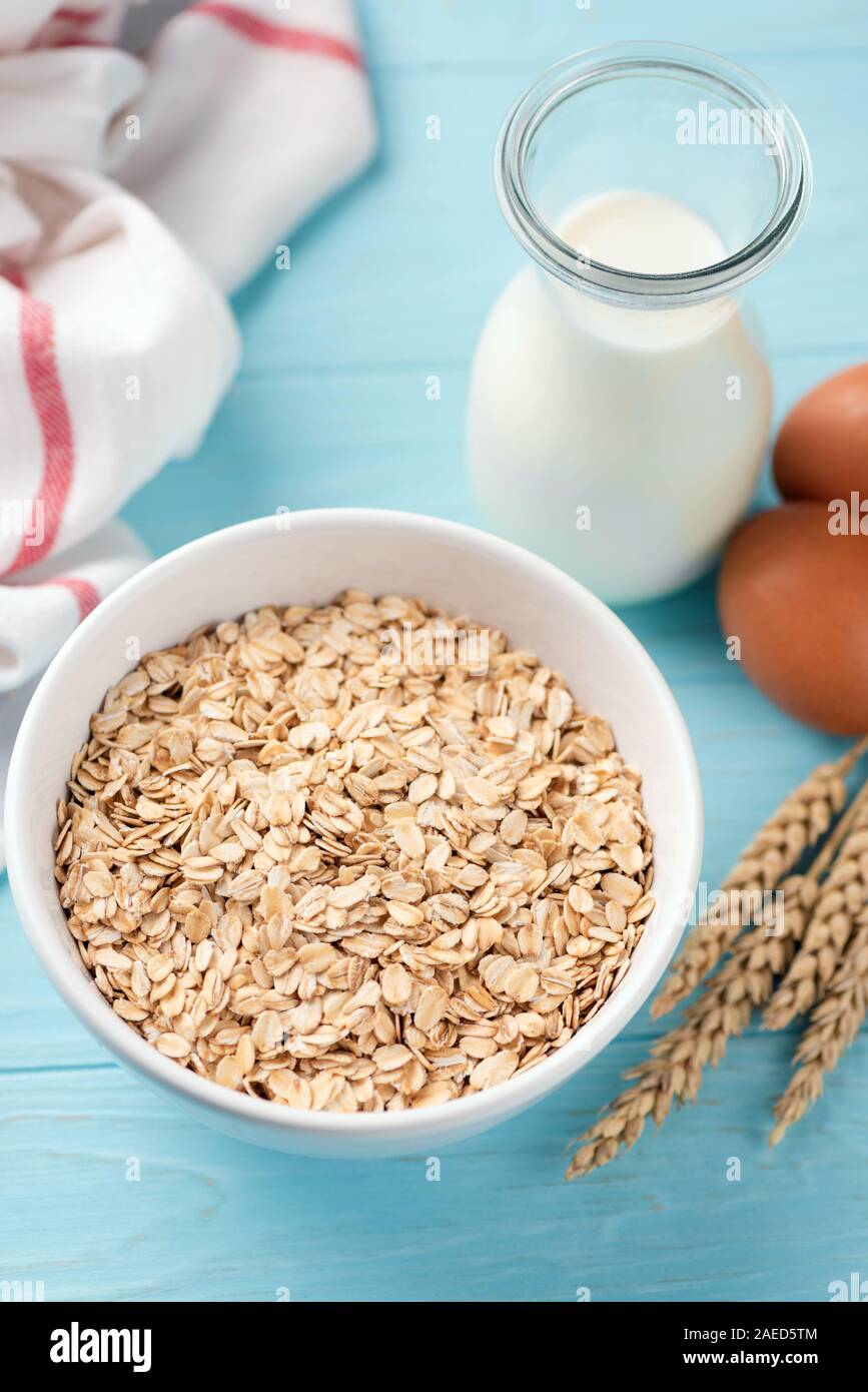 Avena, fiocchi di avena e bottiglia di latte su sfondo blu. Colazione sana nozione di cibo, dieta alimenti Foto Stock