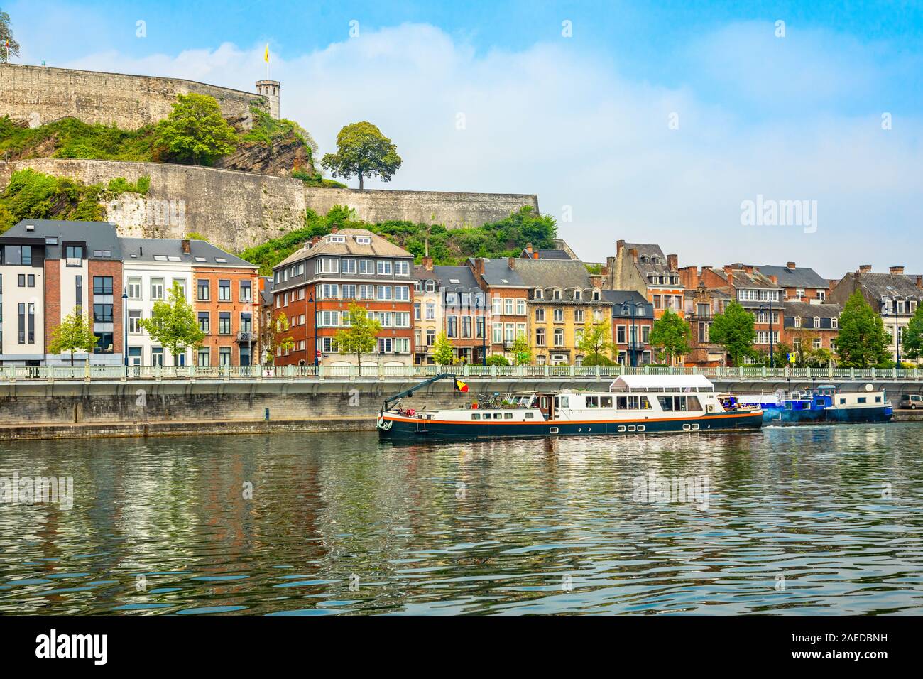 Il fiume Mosa con navi passeggeri e la cittadella di Namur fortezza sulla collina, Namur, la Vallonia, Belgio Foto Stock