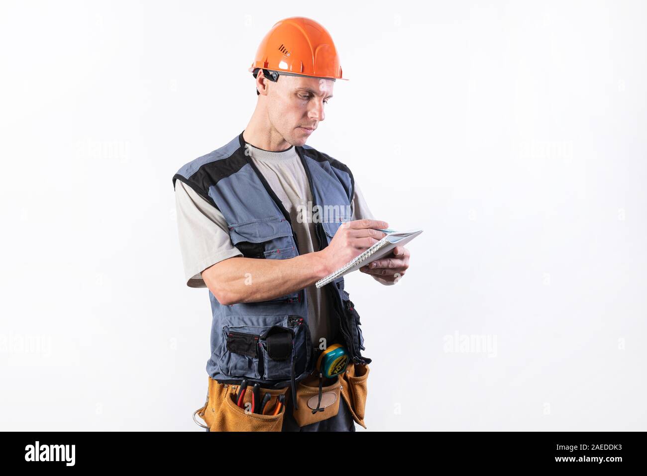 Builder con un blocco note. In un casco e un accappatoio. Scrive i dati. Foto Stock