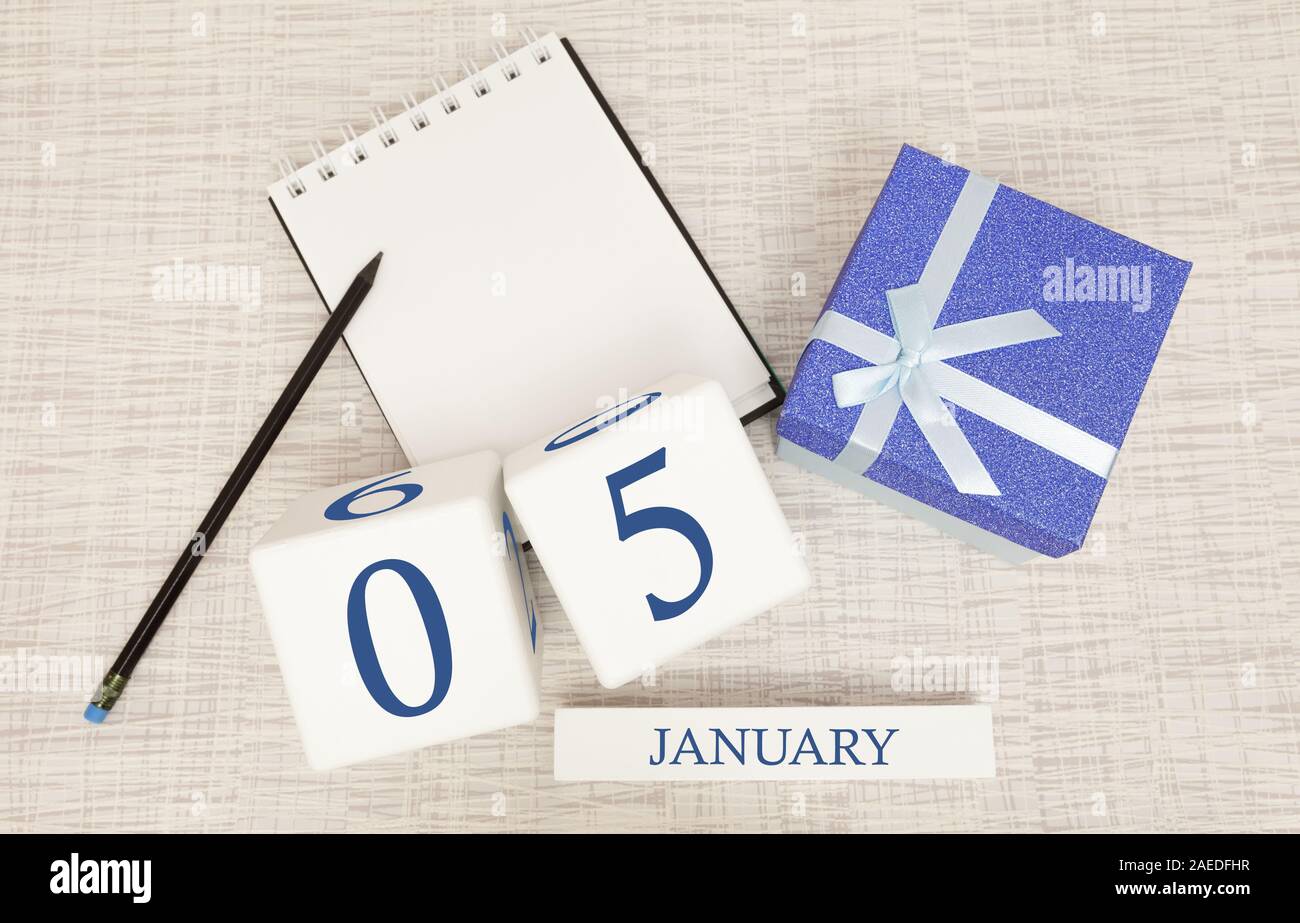 Calendario con blu alla moda il testo e i numeri per il 5 gennaio e un regalo in una scatola. Foto Stock