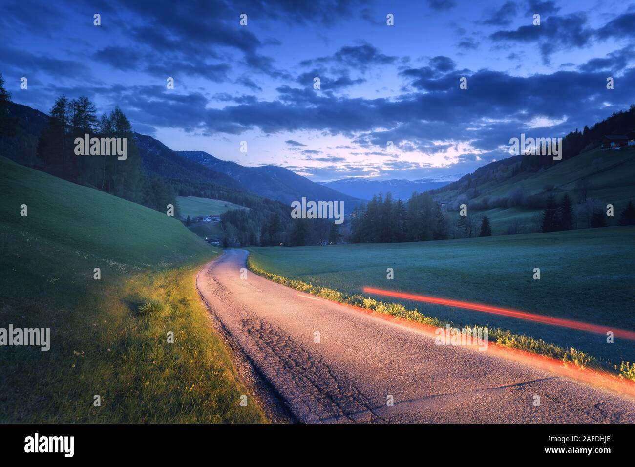 Sfocata fari auto sulla strada rurale di notte in estate Foto Stock