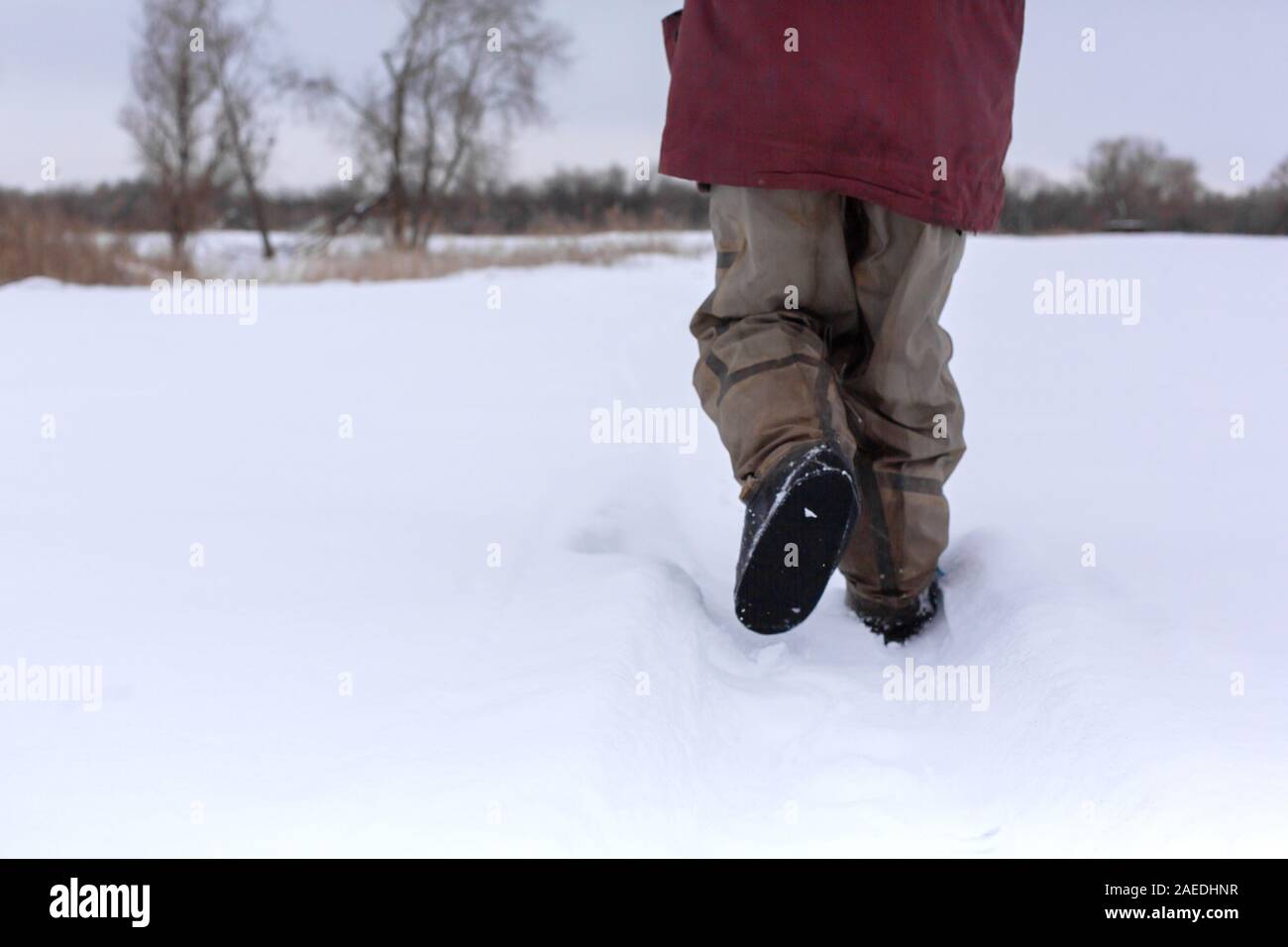 La vista dal retro di un uomo a camminare nella neve in stivali di gomma  Foto stock - Alamy