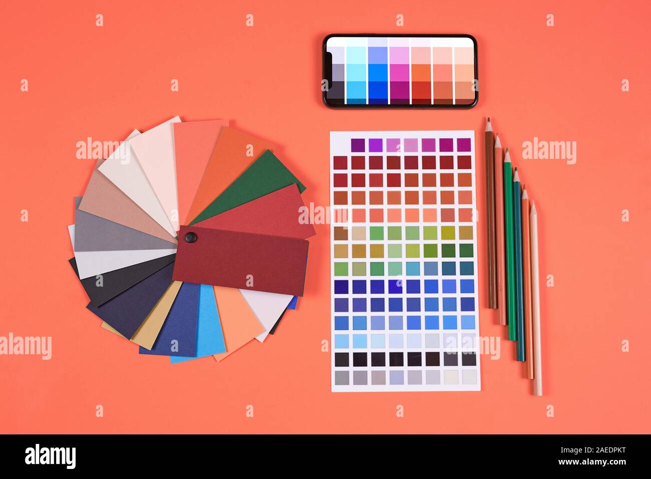 Vista superiore piana dei laici tavolozza dei colori dei campioni e i campioni di cui a designer workplace su sfondo di corallo, spazio di copia Foto Stock
