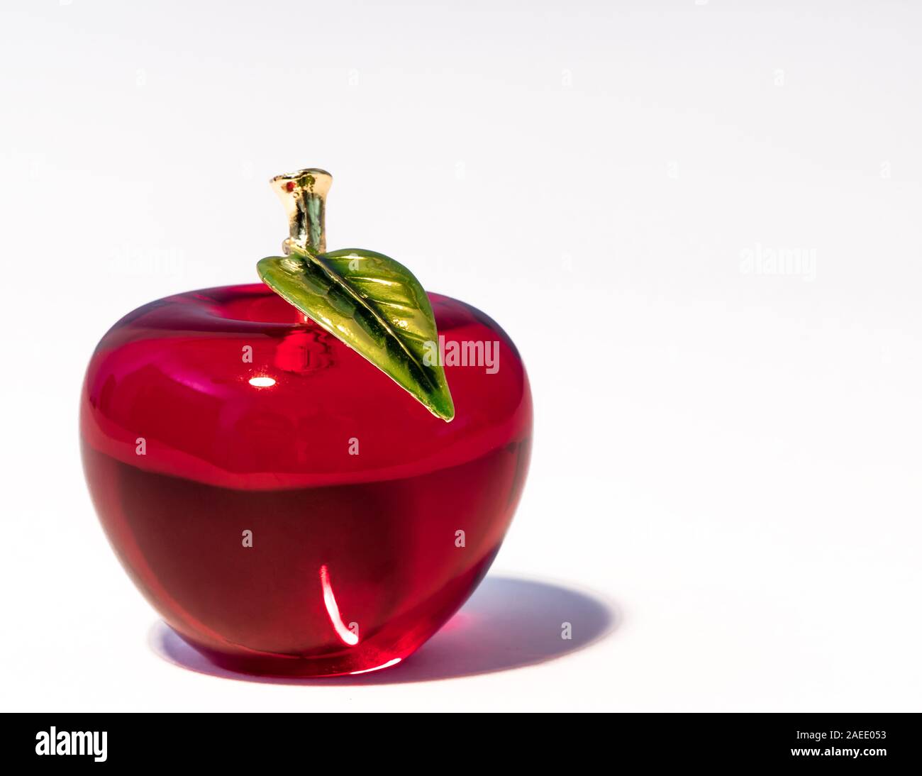 Mela Rossa di Figurine di vetro su sfondo bianco con stelo metallico e foglia. Spazio di copia Foto Stock