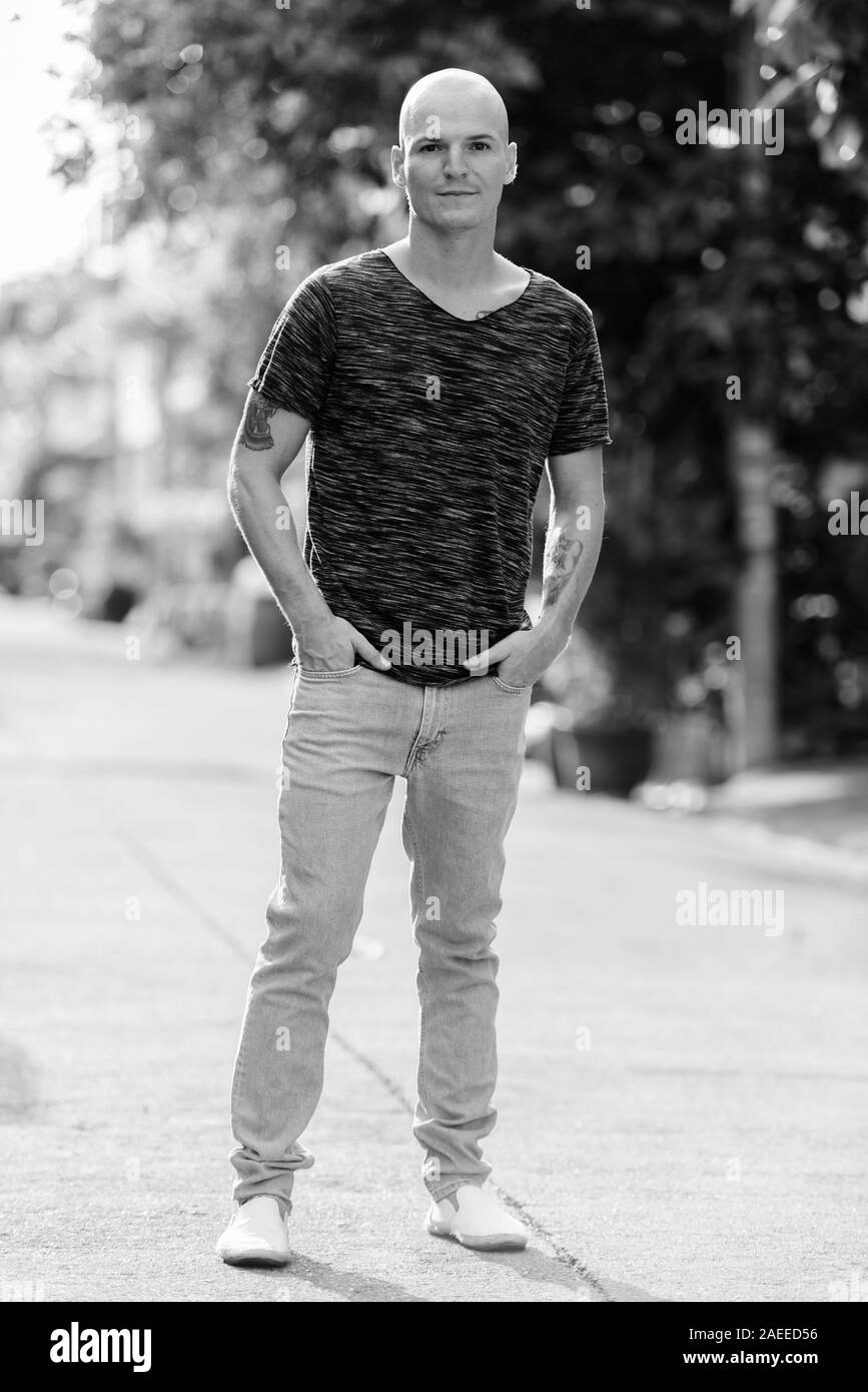 Corpo pieno colpo di giovani bello uomo calvo in piedi all'aperto Foto Stock