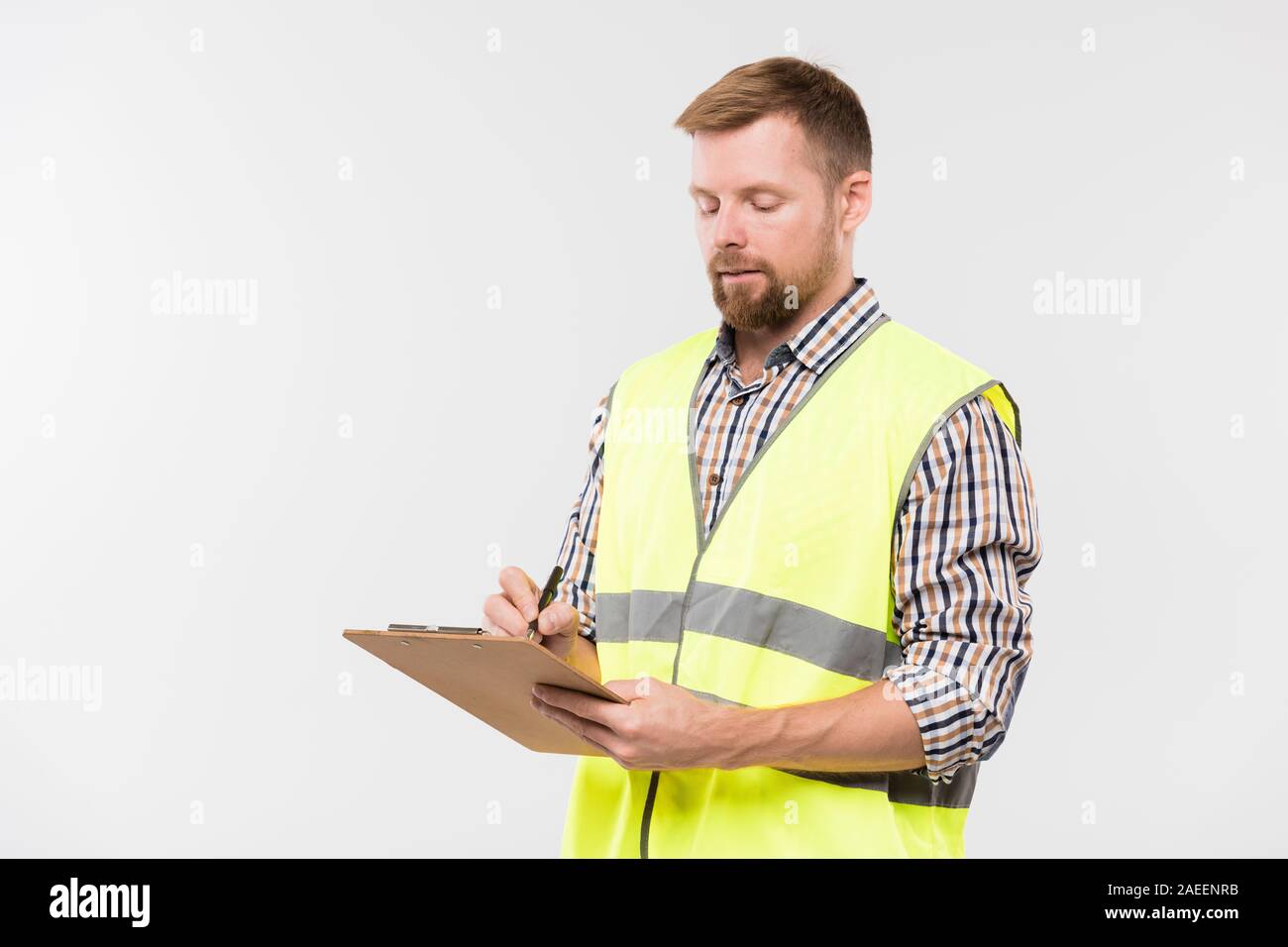 Giovane ingegnere barbuto con appunti e penna rendendo note di lavoro in isolamento Foto Stock