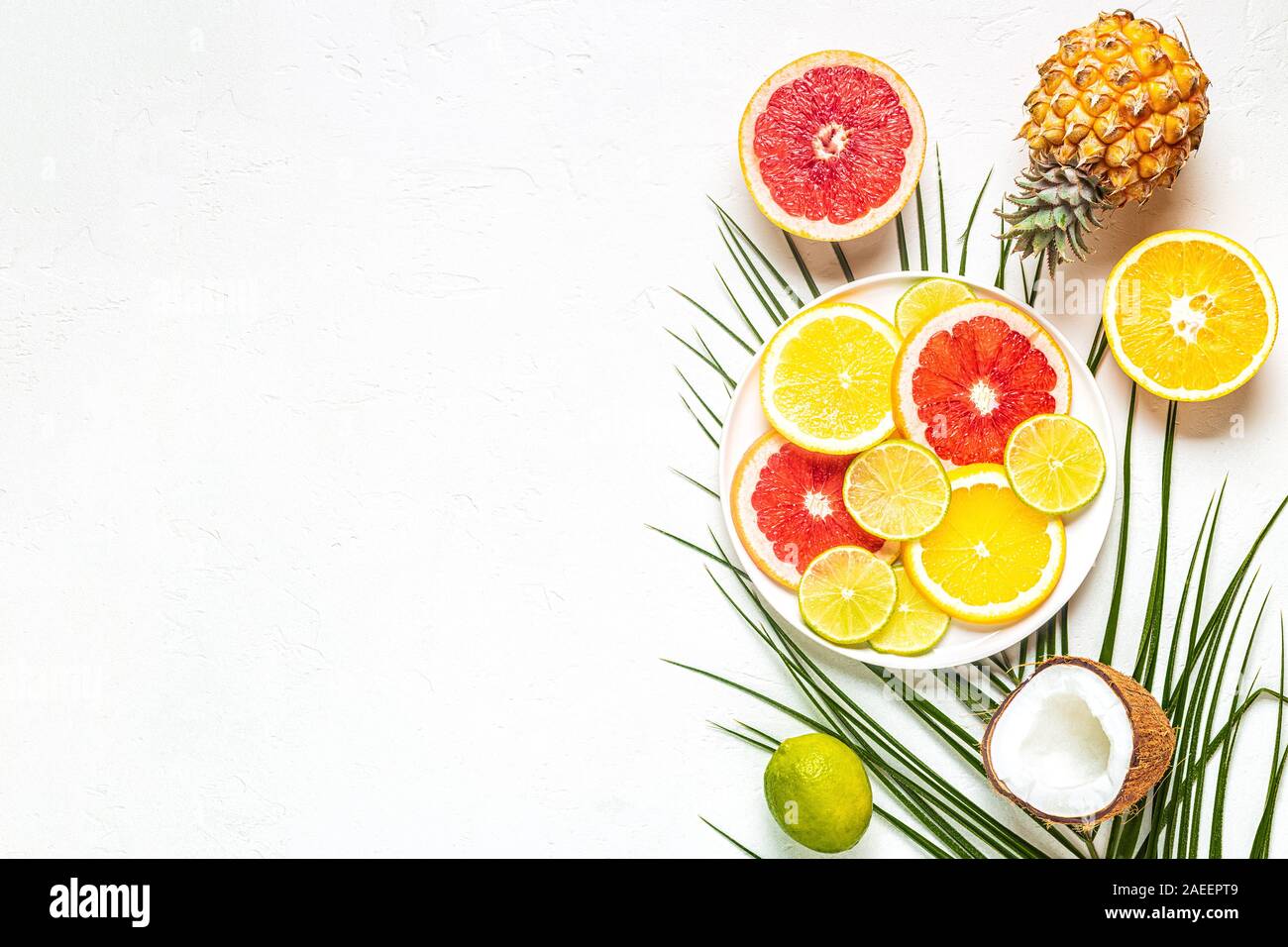 Frutti Tropicali e foglie di palmo su uno sfondo bianco, vista dall'alto. Foto Stock
