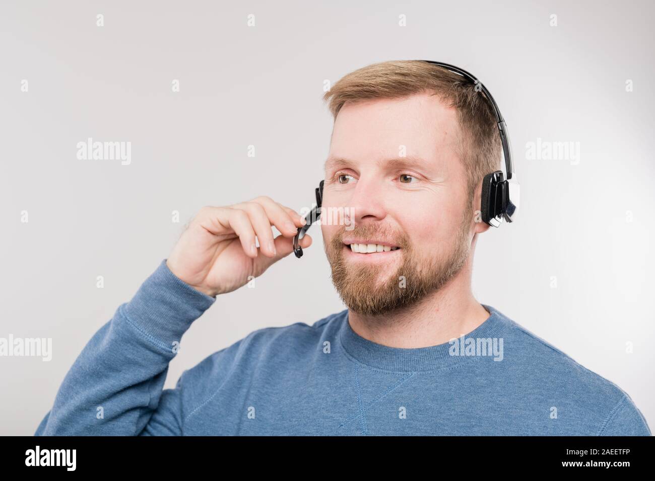 Giovani allegro hotline operatore in cuffia e il blu pullover consulting clienti Foto Stock