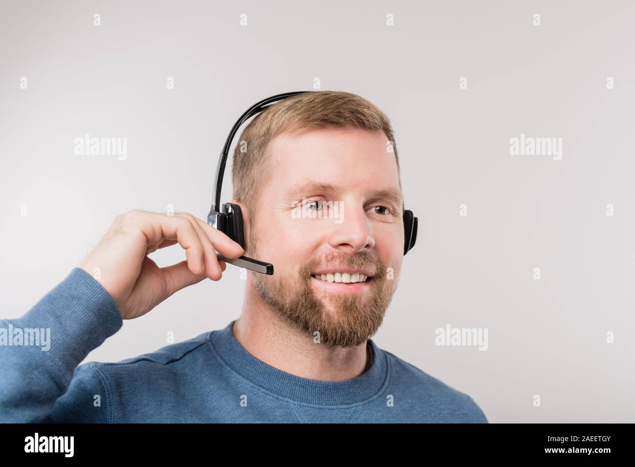 Giovani hotline barbuto operatore in cuffia e informale di client di consulenza Foto Stock