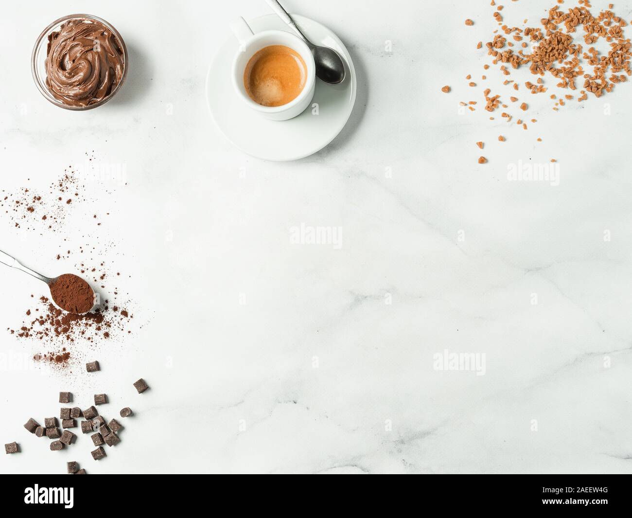 Piatto dolce sfondo laici. Cioccolato, zucchero, nocciola diffusione di cacao, cacao in polvere e la tazza di caffè su marmo bianco piano portapaziente con copia spazio. Si può utilizzare come mock up o offerte speciali per cafe o dolciumi Foto Stock
