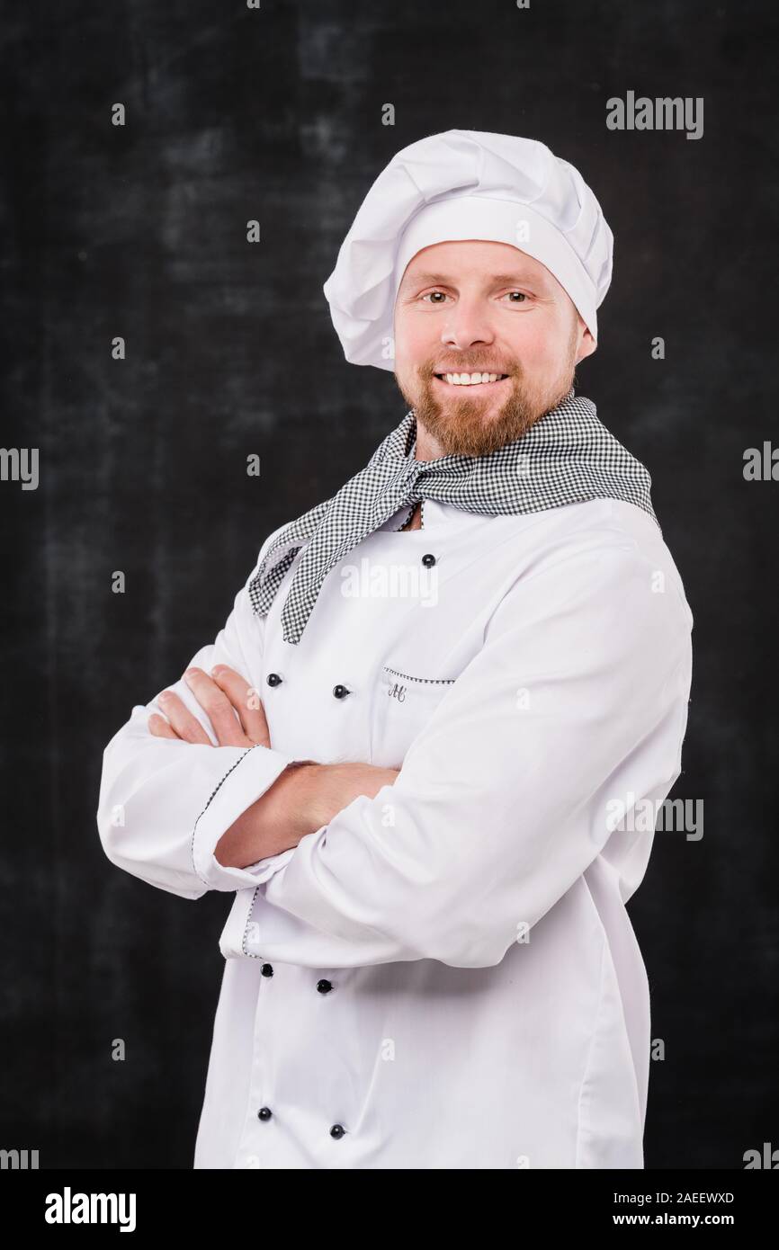 Maschio di successo chef con le sue braccia attraversata dal petto guardando a voi con il sorriso Foto Stock