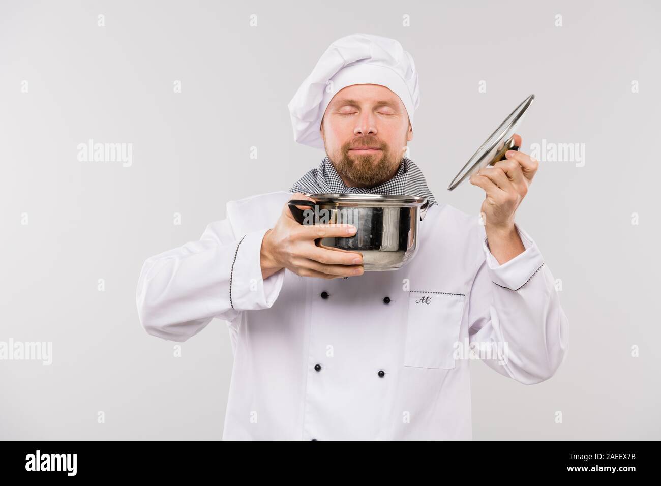 Giovani chef professionale godendo di odore di zuppa o altro pasto cucinato in padella Foto Stock