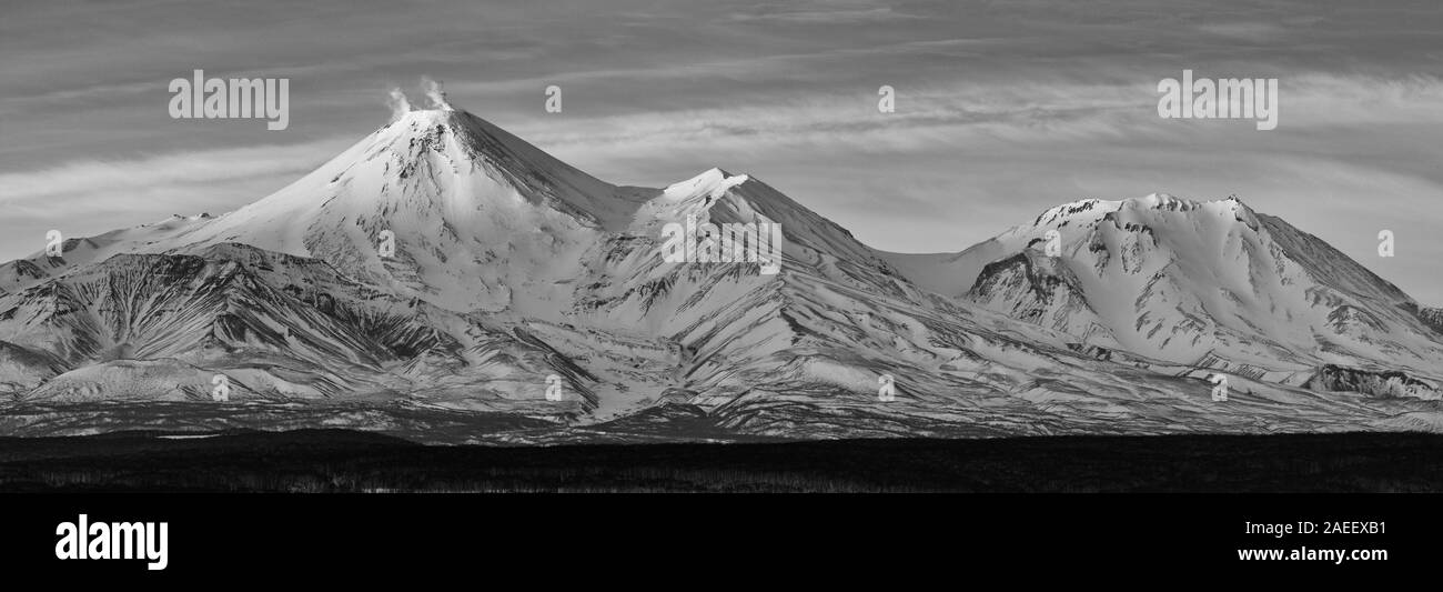 Attivo Vulcano Avachinsky (Vulcano Avacha) eruttando gas, ceneri, fumarola e Kozelsky Vulcano. In inverno il paesaggio panoramico vista sui vulcani della Kamchatka Foto Stock