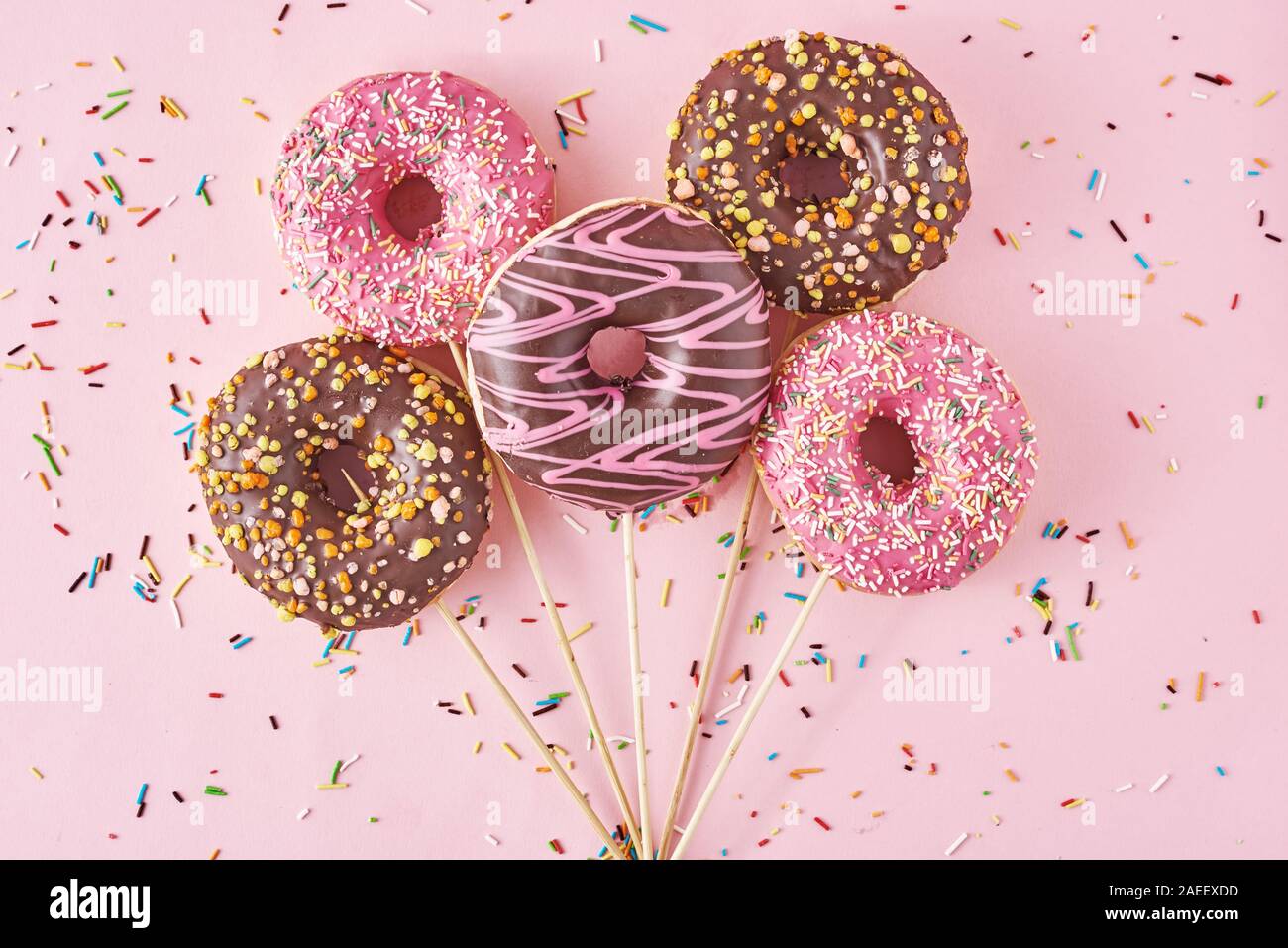 Le ciambelle su sfondo rosa con coriandoli. Cucina creativa stile minimalista Foto Stock