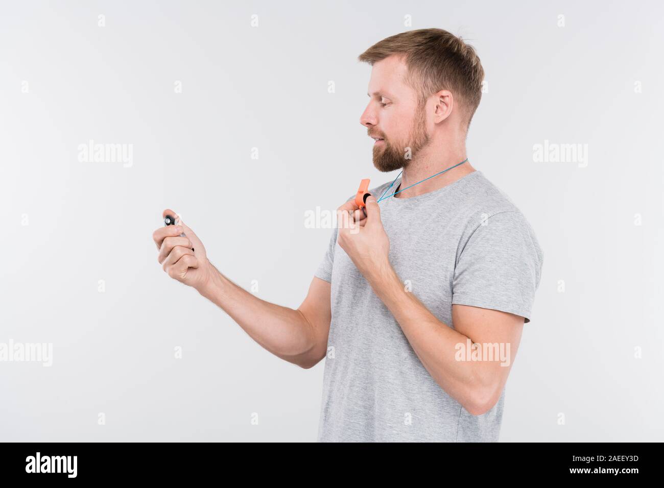 Giovani professionisti trainer con fischietto guardando il cronometro durante il corso di formazione Foto Stock
