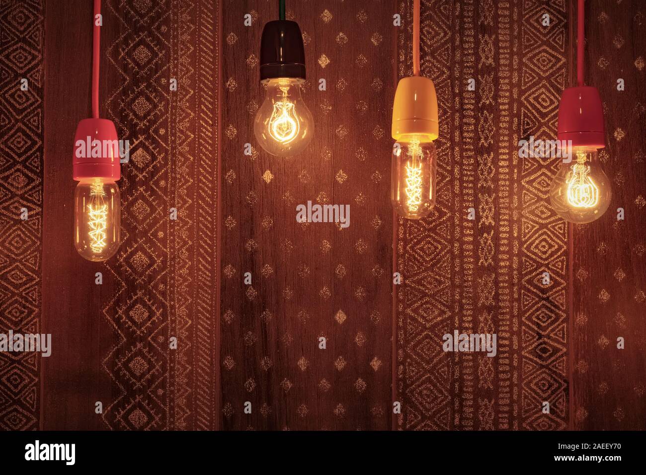 Decorativo lampadine ad incandescenza glow sullo sfondo di una parete con un ornamento. Originale decorazione di interni Foto Stock