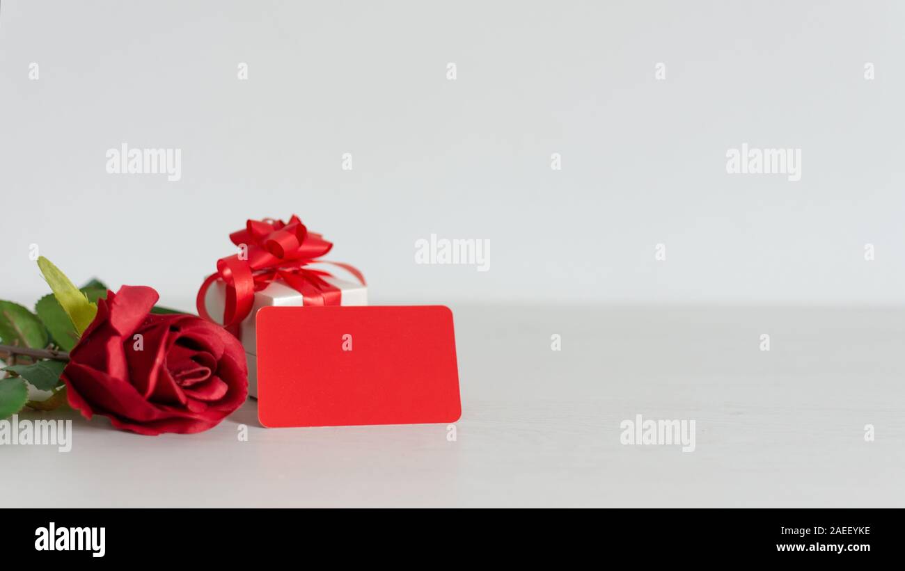 Valentines o regalo di anniversario e un mazzo di bellissime rose rosse con attaccato un rosso blank gift tag per il saluto o il messaggio. Copia dello spazio. Foto Stock