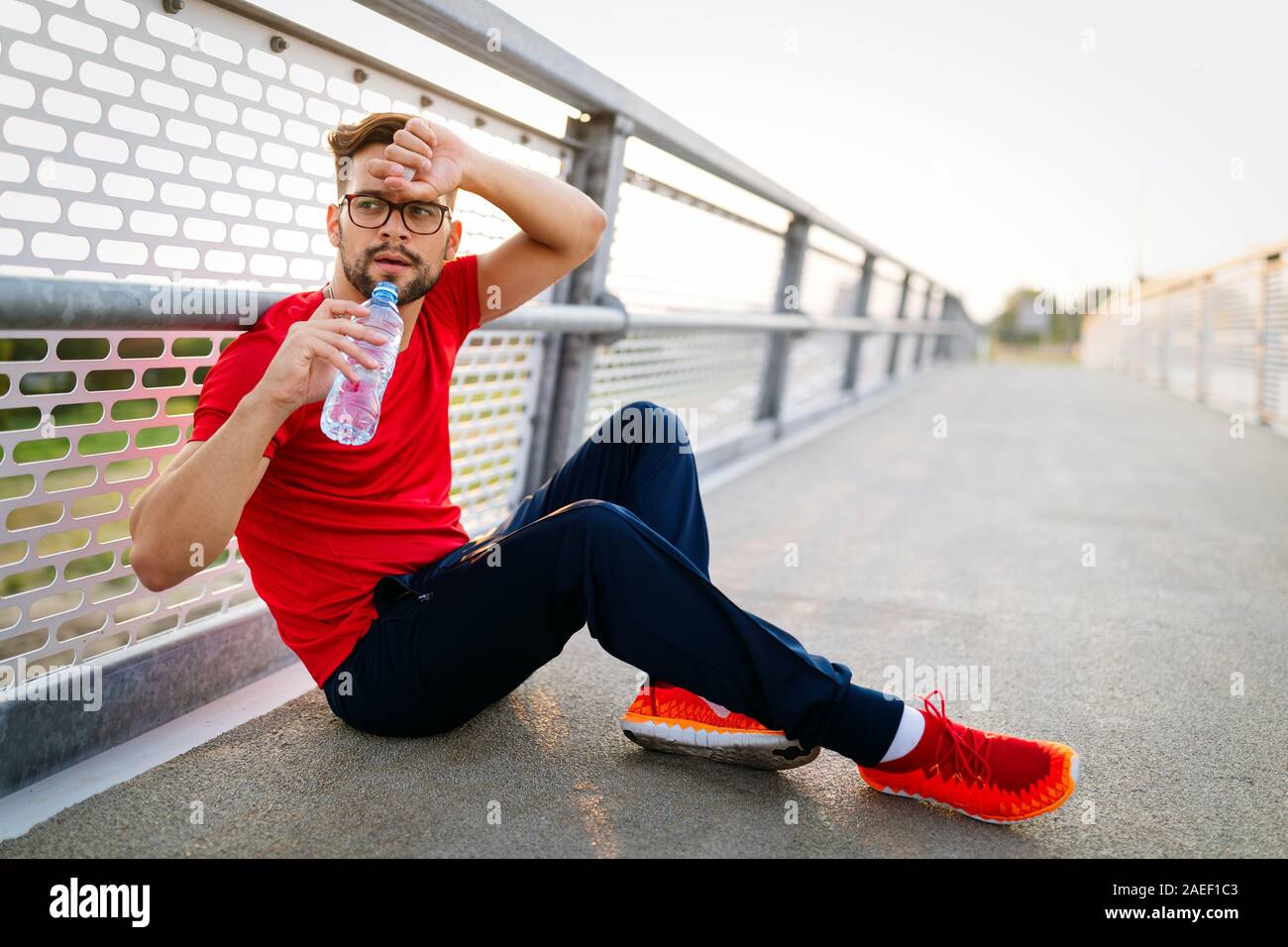 Esecuzione di maschio adulto prendendo una pausa. Stanco esaurito uomo runner sudorazione dopo allenamento cardio. Foto Stock