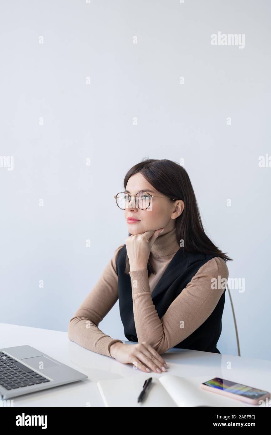 Giovane serio economista femmina concentrandosi su analisi della situazione finanziaria Foto Stock
