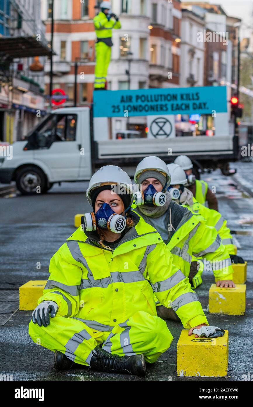 Londra, Regno Unito. 09Dec, 2019. L'aria siamo afflitti: estinzione della ribellione blocco Cranbourne Street, al di fuori della stazione di Leicester Square, alla domanda di azione su 'Deadly' inquinamento dell'aria. La diga include 25 brezza blocchi incollati alla strada per simboleggiare il 25 londinesi che muoiono ogni giorno a causa di inquinamento atmosferico e otto persone sono incollate sui blocchi. Estinzione Rebellion dodici giorni di crisi per garantire il clima e l'emergenza ecologica è in cima all'ordine del giorno questa elezione generale. Credito: Guy Bell/Alamy Live News Foto Stock