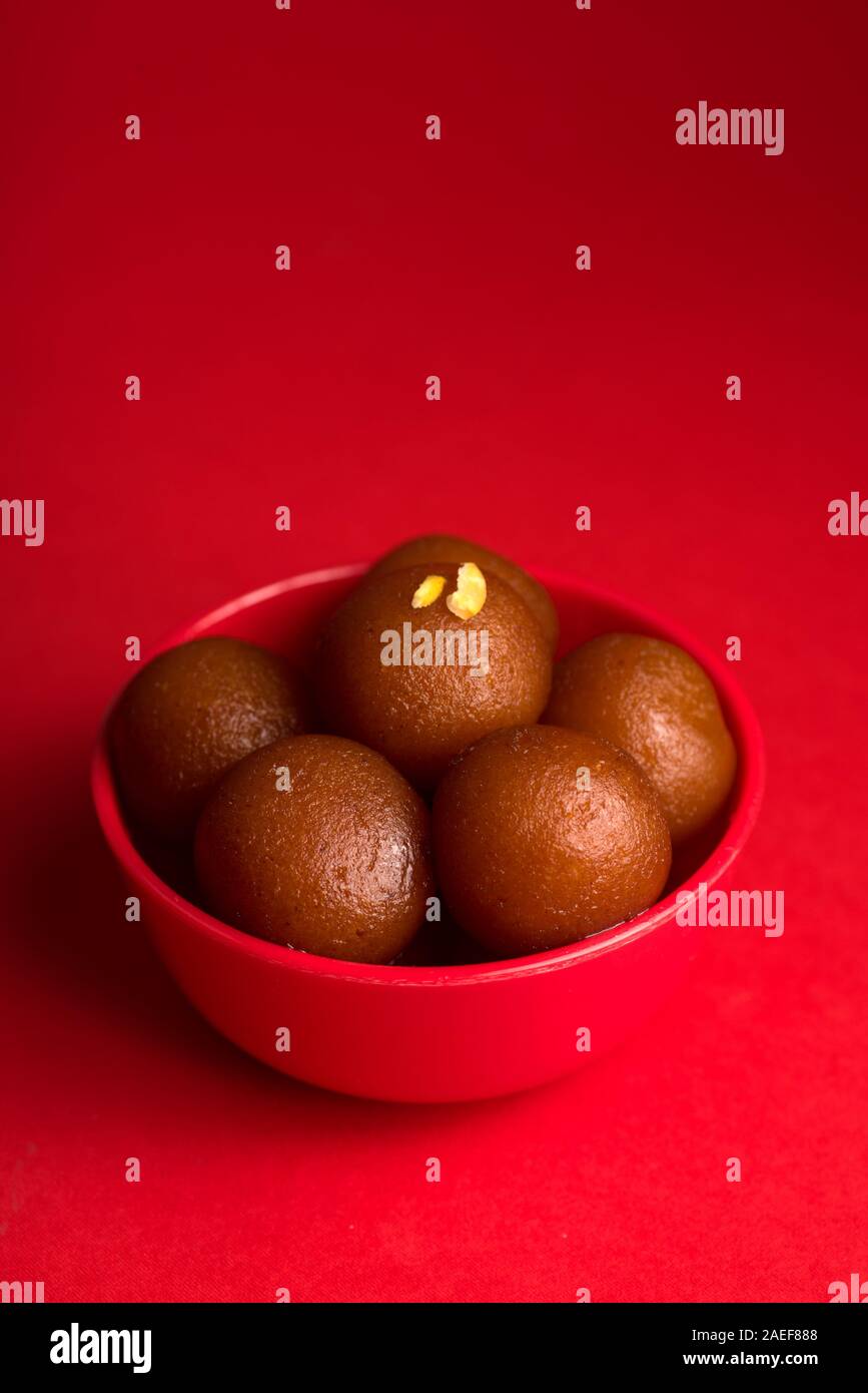 Gulab Jamun nel recipiente rosso su sfondo rosso. Indian dessert o un piatto dolce. Foto Stock