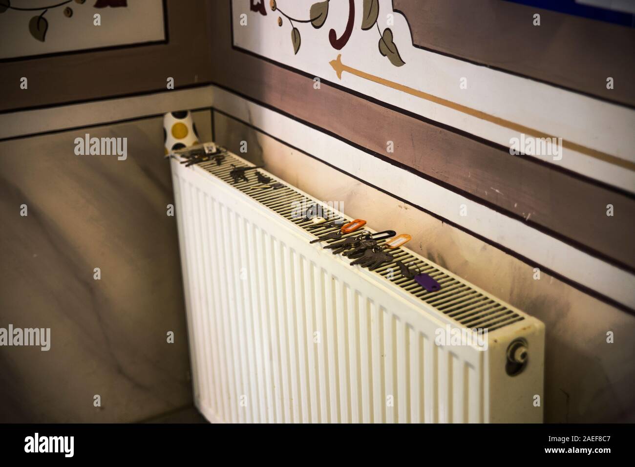 Tasti per molte porte a sinistra su un contemporaneo il radiatore di riscaldamento di un classico interno con pareti a ricamo. Concetto chiave per le soluzioni di progettazione e problemi. Foto Stock