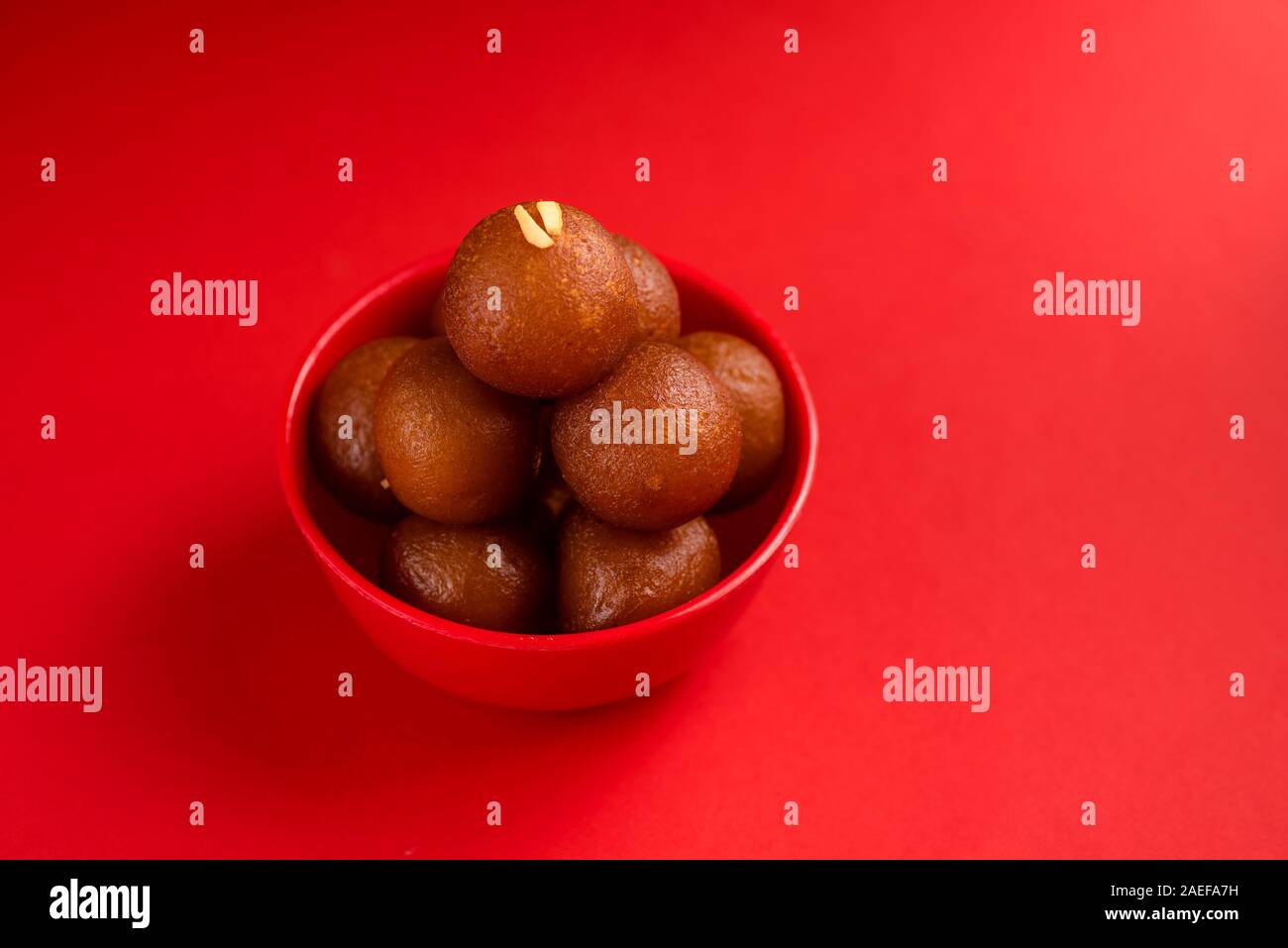 Gulab Jamun nel recipiente rosso su sfondo rosso. Indian dessert o un piatto dolce. Foto Stock