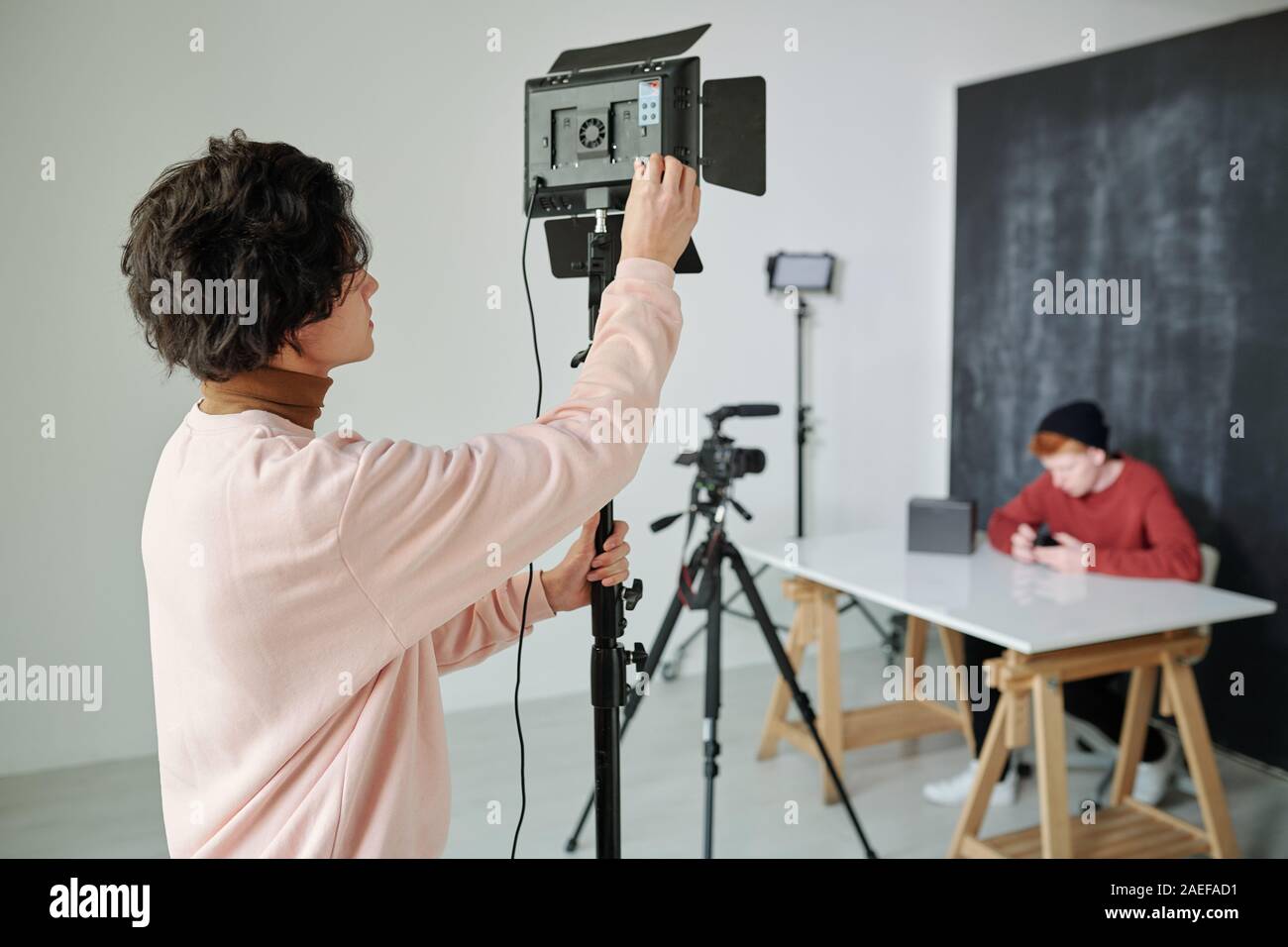 Giovani cameraman in informale preparare video apparecchiature di ripresa Foto Stock