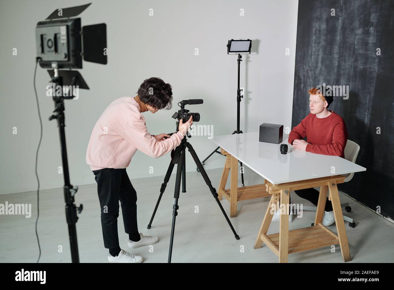 Giovani cameraman piegatura nella parte anteriore del video di apparecchiature di ripresa in studio Foto Stock