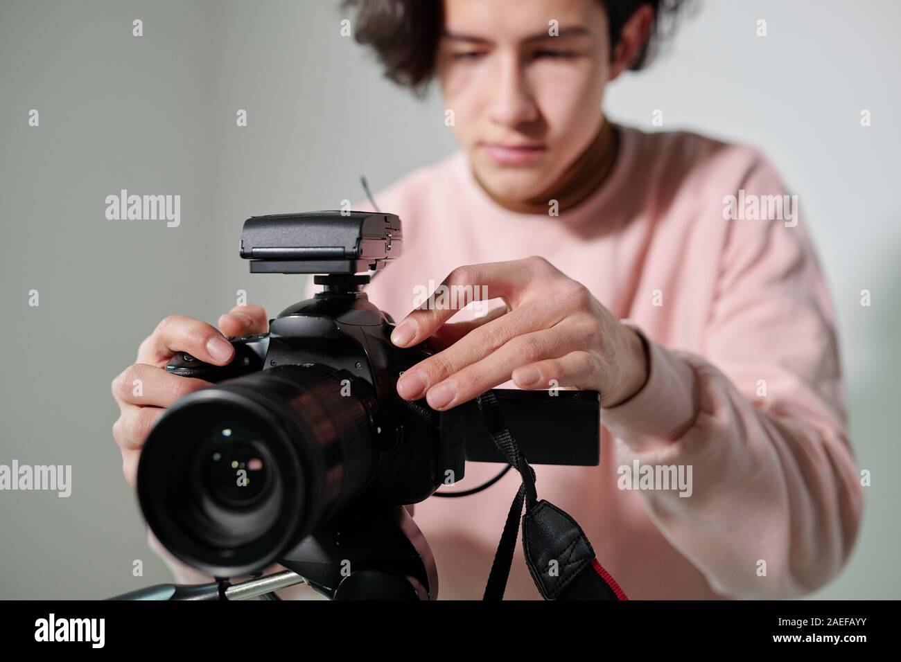 Le mani del giovane cameraman in rosa polverulento felpa regolazione di apparecchiature video Foto Stock