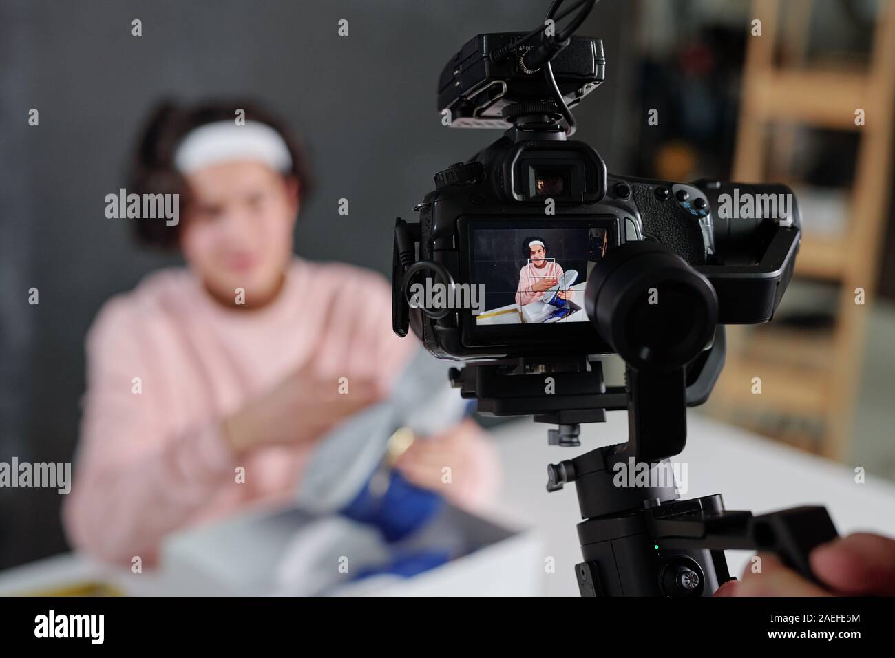 Giovani vlogger in informale che mostra sneakers sul display della videocamera digitale Foto Stock