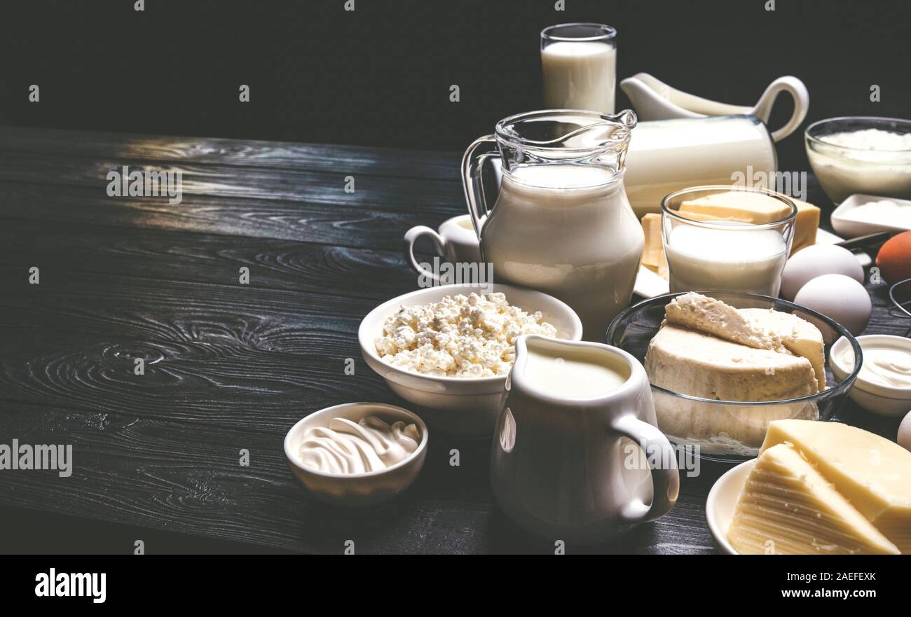 Prodotti lattiero-caseari sul legno nero, sfondo foto filtrata in stile vintage Foto Stock