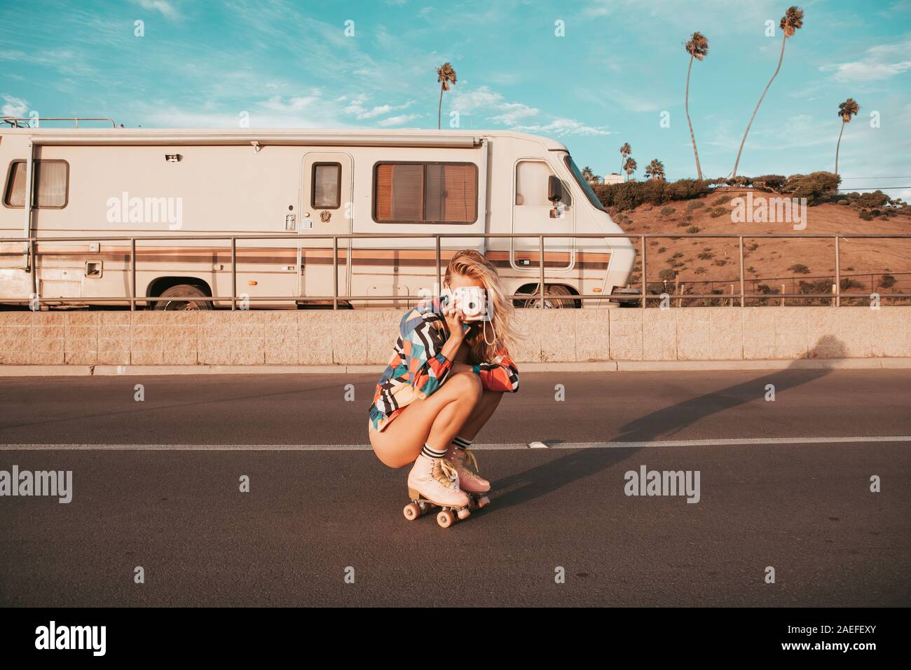 In stile retrò skater ragazza con un camper in background. california lifestyle Foto Stock