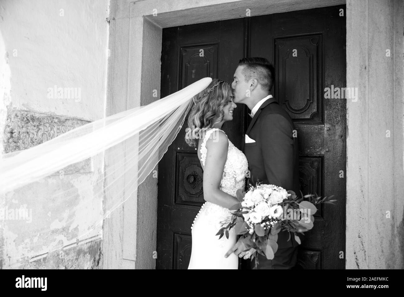 Il bacio. Lo sposo baci sposa sulla fronte di fronte alla chiesa del portale. Foto Stock