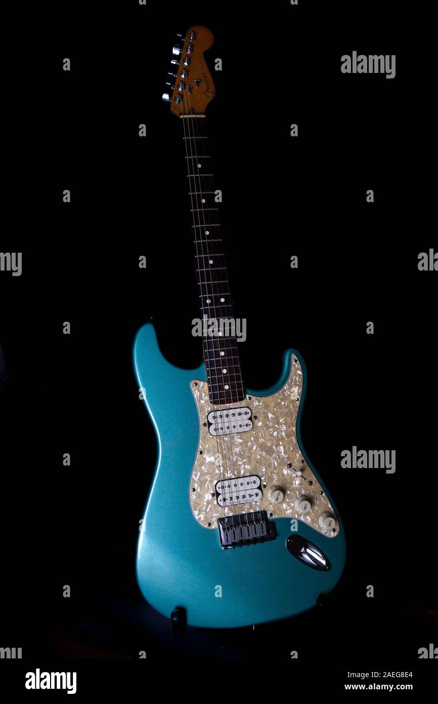 Ritratto di una luce blu chitarra elettrica su uno sfondo nero. Foto Stock