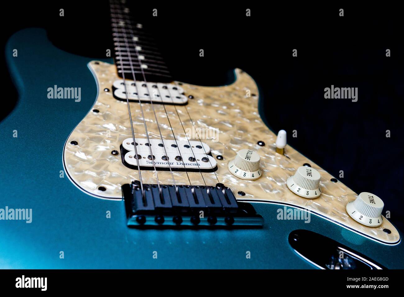 Un dettaglio di una luce blu chitarra elettrica su uno sfondo nero. Foto Stock