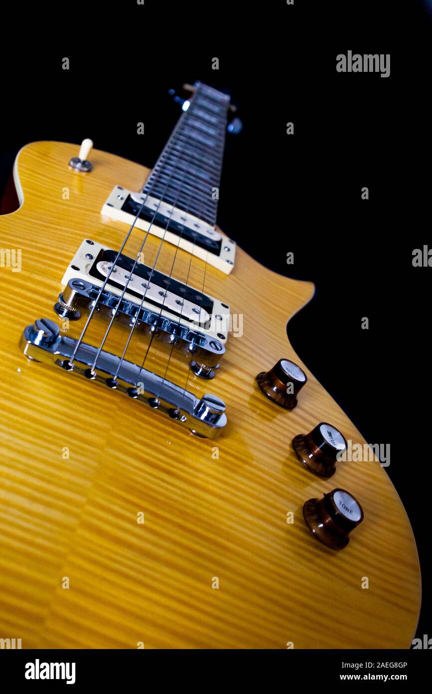 Un dettaglio di una chitarra di legno su uno sfondo nero Foto Stock